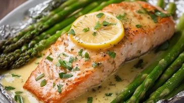 Saumon cuit au four dans du papier d'aluminium avec des asperges et une sauce au beurre à l'ail et au citron