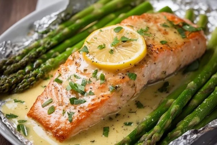 Saumon cuit au four dans du papier d'aluminium avec des asperges et une sauce au beurre à l'ail et au citron